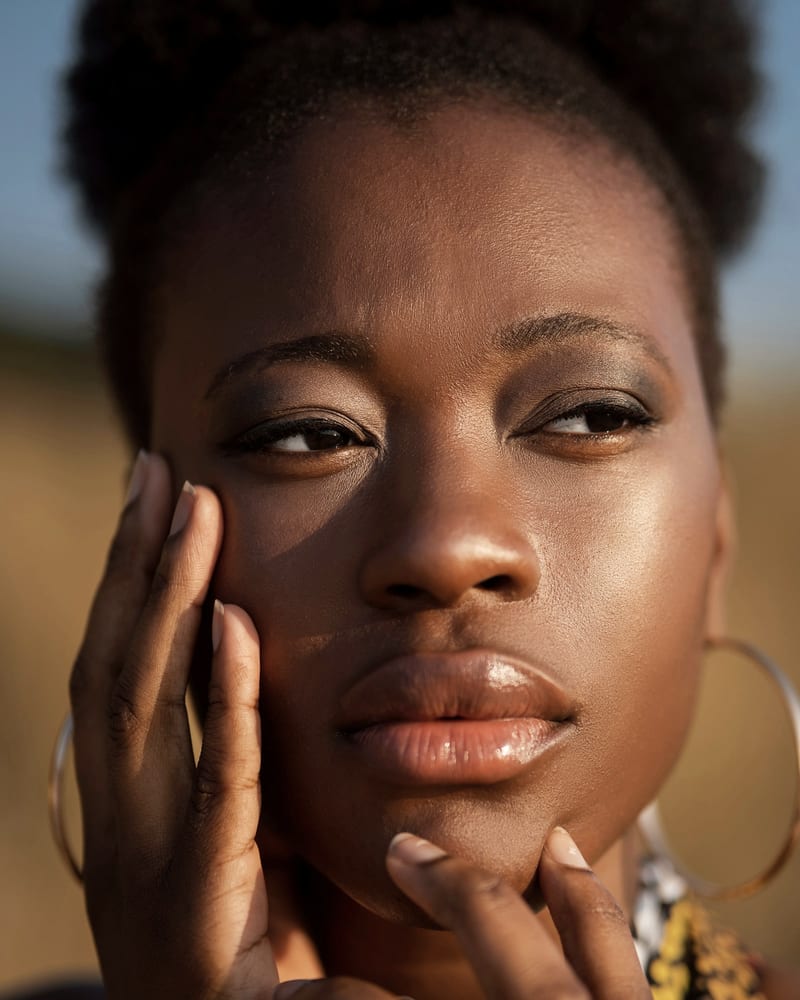 A woman resting her hand against her cheek in golden light