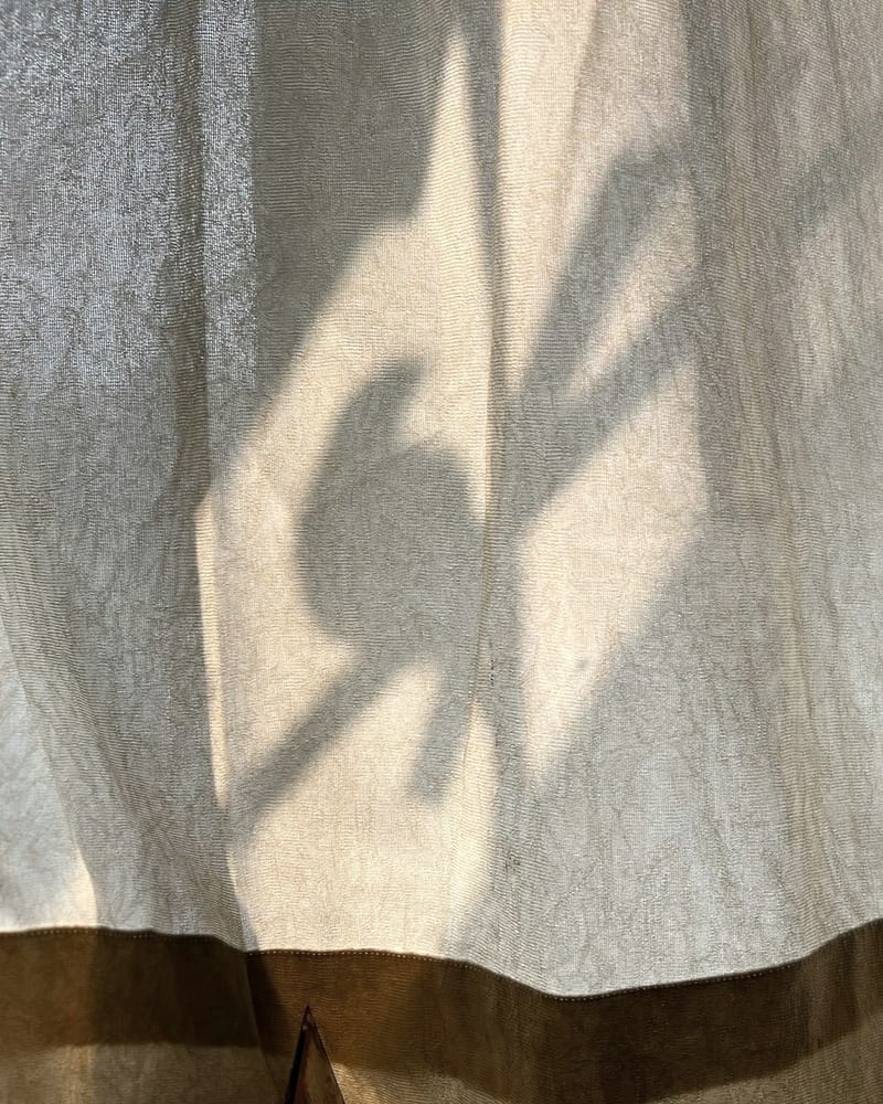 Leaf shadow moving across a linen curtain